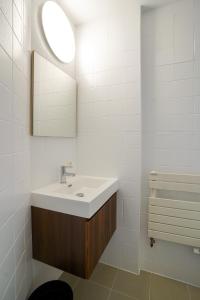 een witte badkamer met een wastafel en een spiegel bij Cinquantenaire 1 in Brussel