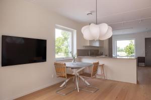 a dining room with a table and a flat screen tv at Luxury Living at Ekerum Öland Heated Pool, Golf & Sea! in Borgholm +13 photos