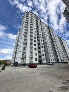 ein großes weißes Gebäude mit einem roten Auto vor dem Haus in der Unterkunft Kutaisi Apartment 54 in Kutaissi