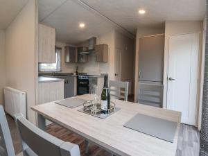 a kitchen and dining room with a table with a bottle of wine at Meadows Park 4 in Hull +11 photos