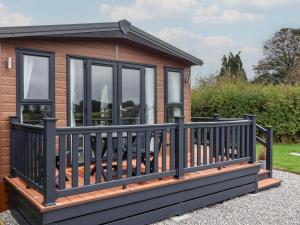 a tiny house with a black railing on a deck at Meadows Park 1 in Hull