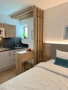a bedroom with a bed and a small kitchen at Apartmenthaus Blauer Wolf by ROom for LIving Gunzenhausen in Gunzenhausen