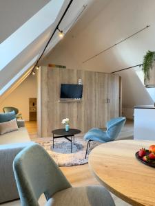 a living room with a couch and chairs and a tv at Apartmenthaus Blauer Wolf by ROom for LIving Gunzenhausen in Gunzenhausen