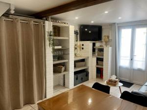 a living room with a table and a tv on a wall at Ma Toquade in Quiberville