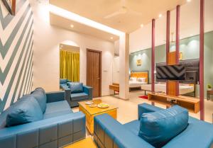a living room with blue couches and a television at Shamrock Greens by Jardin Hotels in Dharmpura