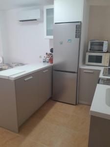 a white kitchen with a refrigerator and a microwave at APARTAMENTO EL TIMON in Carboneras +25 photos