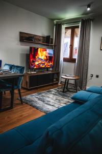 a living room with a blue couch and a tv at VujSki - Gondola Apartman in Brzeće