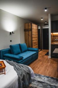 a living room with a blue couch and wooden floors at VujSki - Gondola Apartman in Brzeće