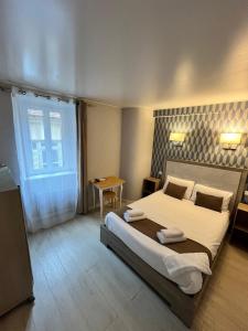 Un dormitorio con una cama grande y una mesa. en Hotel du Nord - Ville-Haute, en Saint-Flour