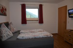 Una cama sentada en una habitación con ventana. en Appartement Wieshof, en Neukirchen am Großvenediger