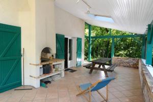 a patio with green doors and a table and a bench at Chambres d'hotes du Prieur in Léognan +5 photos