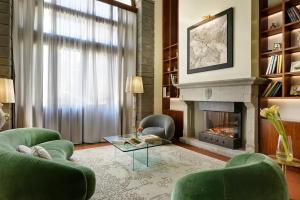 a living room with a fireplace and green chairs at Hotel Kraft in Florence
