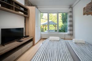 sala de estar con TV de pantalla plana y 2 camas en Arborétum Nyaraló Szarvas - Kültéri jakuzzival, en Szarvas