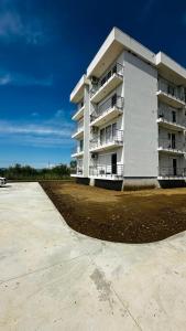 a large white apartment building with a parking lot at Apartamente me qera tale plazh lezhë in Lezhë