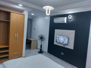 ein Schlafzimmer mit einer Wand, an der ein Fernseher und ein Ventilator hängen. in der Unterkunft Apartments in Lekki in Lekki