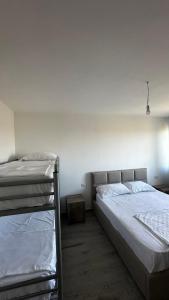 a bedroom with two beds and a white wall at Apartamente me qera tale plazh lezhë in Lezhë