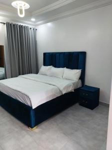 Bett mit blauem Kopfteil in einem Schlafzimmer in der Unterkunft Apartments in Lekki in Lekki