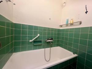 a green tiled bathroom with a bath tub at City apartment with balcony in Norrköping