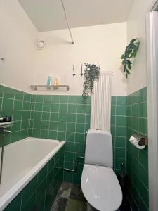 a green tiled bathroom with a toilet and a tub at City apartment with balcony in Norrköping