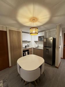a kitchen with a white table and a refrigerator at Frente a Playa Brava, Cerca Cavancha, WiFi in Iquique