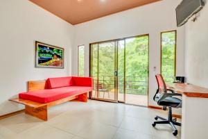 a living room with a red couch and a desk at Antema Lodge Secteur Tamarindo, piscine, yoga, gym, jungle et paix in Tamarindo
