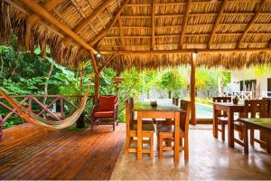 a patio with a hammock and tables and chairs at Antema Lodge Secteur Tamarindo, piscine, yoga, gym, jungle et paix in Tamarindo