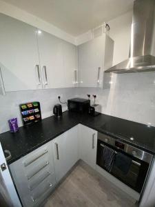 a kitchen with white cabinets and a black counter top at Luxe Apartment in Croydon +6 photos