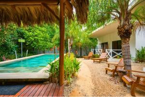 a swimming pool with benches and a house at Antema Lodge Secteur Tamarindo, piscine, yoga, gym, jungle et paix in Tamarindo