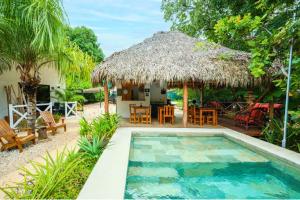 a villa with a swimming pool and a hut at Antema Lodge Secteur Tamarindo, piscine, yoga, gym, jungle et paix in Tamarindo