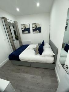 a bedroom with a bed with white sheets and blue pillows at Luxe Apartment in Croydon