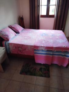 a bedroom with a bed with a pink comforter at Le petit couin des voyageurs in Bouillante