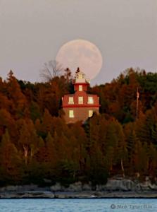un phare sur une colline avec la lune en arrière-plan dans l'établissement Blueberry Cottage Lake Champlain, à Plattsburgh