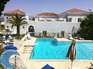 a swimming pool in front of a large house at Oltremare Inn in Spetses