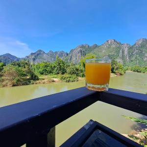 a glass of beer sitting on a balcony overlooking a river at vangvieng SCK Hotel in Vang Vieng