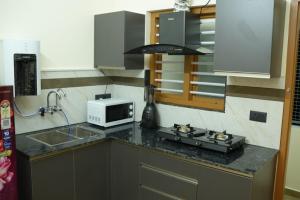 a kitchen with a stove and a microwave on a counter at Joen homes apartment in Alwaye