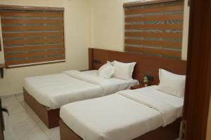 two beds in a hotel room with white sheets at Joen homes apartment in Alwaye