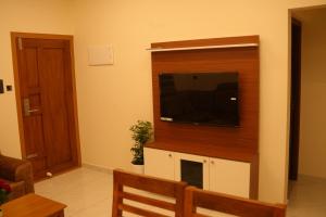 a living room with a flat screen tv on a wall at Joen homes apartment in Alwaye