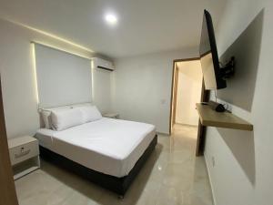 a bedroom with a white bed and a television at Apartamento Sabaii 201 in Cartagena de Indias