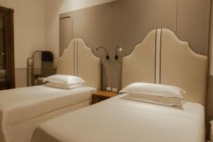 two beds with white sheets in a room at Hotel Casa Bianca by Faranda Boutique in Cartagena de Indias