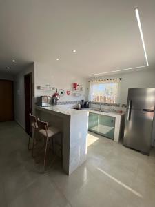 eine Küche mit einer Theke und einem Kühlschrank aus Edelstahl in der Unterkunft Casa com ar condicionado, churrasqueira e rooftop in Alto Paraíso de Goiás