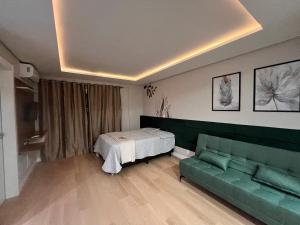 ein Wohnzimmer mit einem Bett und einem grünen Sofa in der Unterkunft Loft Super aconchegante a 50mt da Vila Germânica com estacionamento gratuito in Blumenau + 4 Fotos