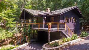 a purple house with a deck in the woods at Elk Watch at Hound Ears in Valle Crucis