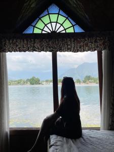 a woman sitting in a window looking out at the water at HB Freedom group of Houseboats in Srinagar