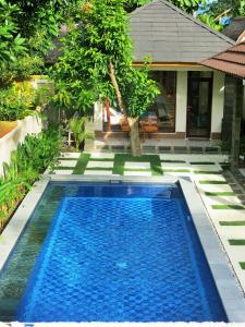 una piscina de agua azul frente a una casa en Two Brothers Villa, en Gili Air