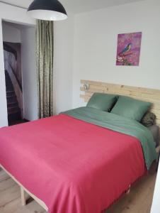 a bedroom with a large bed with a red blanket at petite maison sans vis a vis in Thoirette