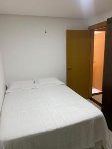 Un dormitorio con una gran cama blanca y una puerta en Mirante, en Parnamirim