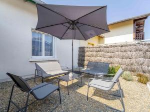 a patio with a table and chairs and an umbrella at Maison rénovée à Mimizan pour 10 pers. avec jardin proche océan - FR-1-50-194 in Mimizan