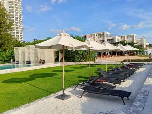 a row of umbrellas and lounge chairs next to a pool at Stay with me by Veranda Resident in Na Jomtien