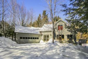 a white house with a snow covered driveway at Spruce Pond Haven in Stowe