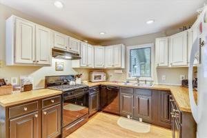 a kitchen with wooden counters and white cabinets at Spruce Pond Haven in Stowe